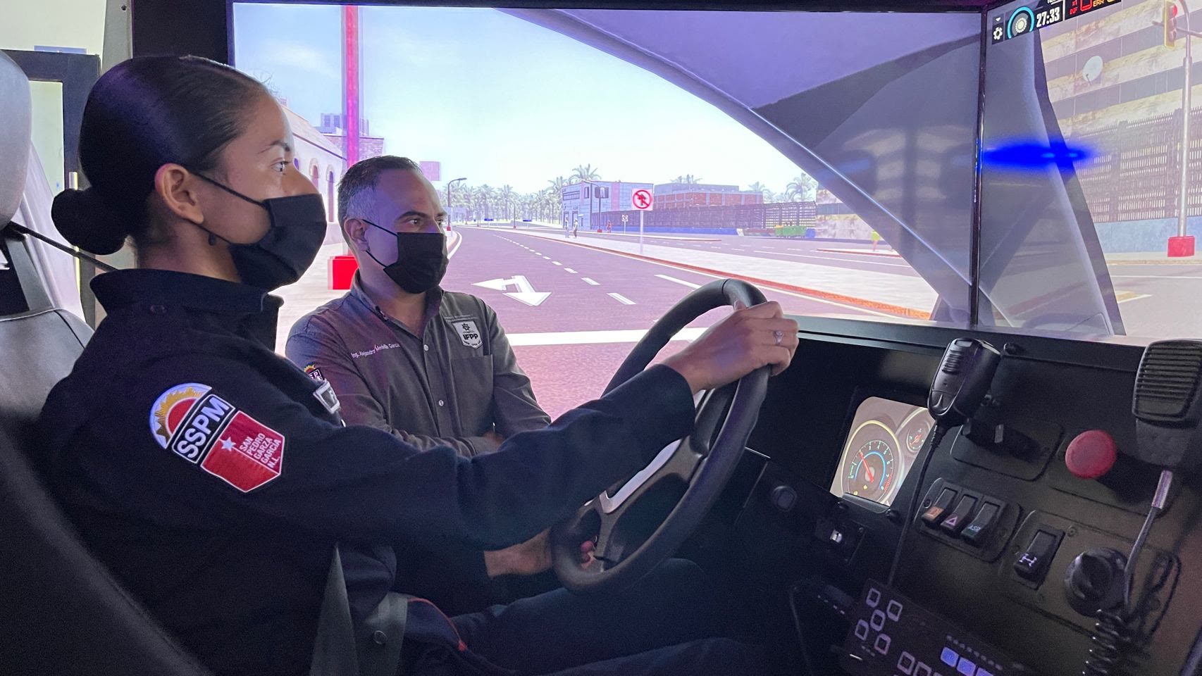 Elemento de la policía de San Pedro al volante del simulador de patrulla, con su instructor al lado